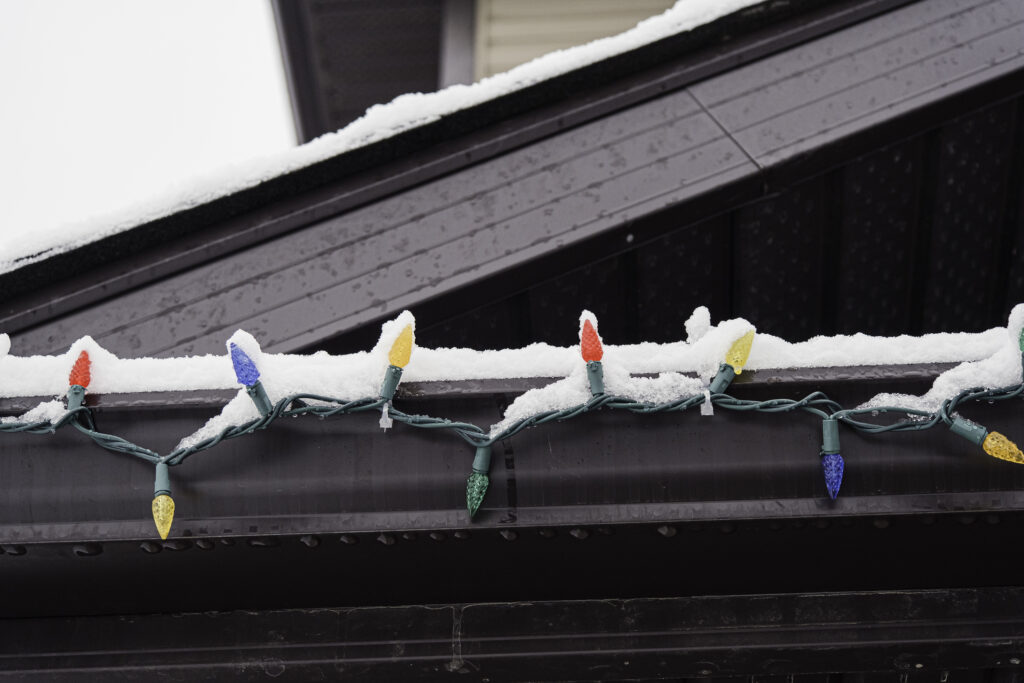 Lights hanging on roof of house, part of exterior holiday decorating.