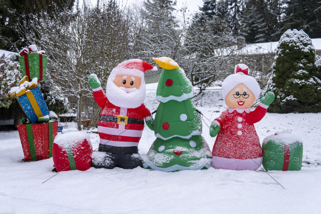 Inflatable figures of Santa Claus, Christmas tree, Santa's wife and boxes with gifts in the snow.