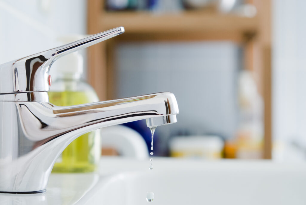 A closeup of a bathroom faucet dripping water.