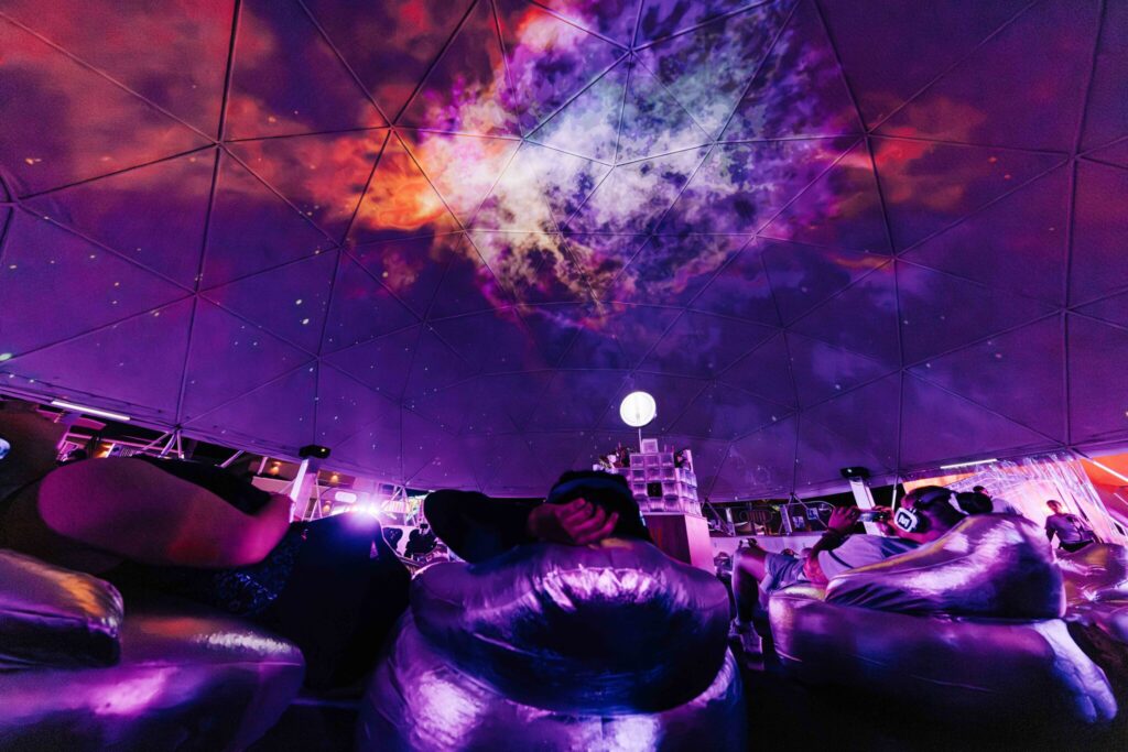 Quest attendees lounge in night-time astral planetarium experience.