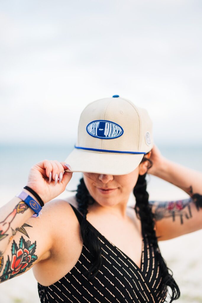 An employee poses in the "Best of Quest" hat on the beach.