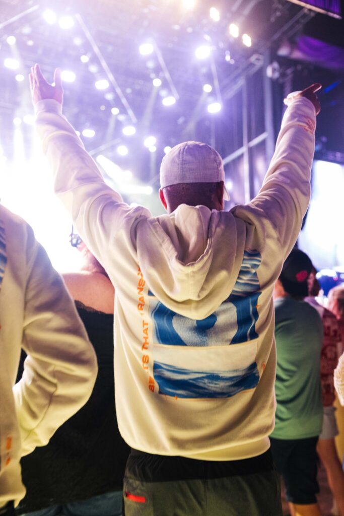 an employee posing for a photo during the festival showing off the back of the POWER x Standard Issue cream sweatshirt.