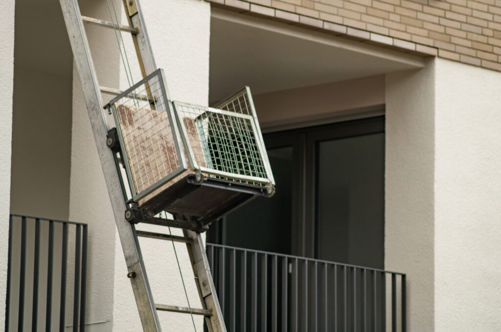 a ladder hoist carrying things up a ladder outside of a building.