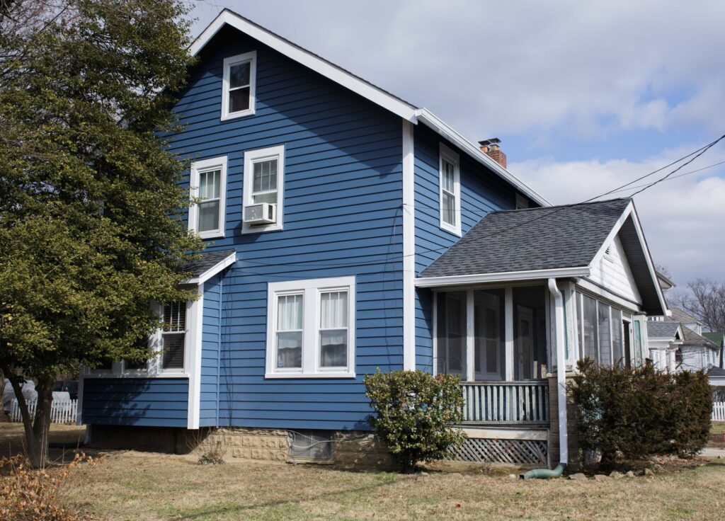 A blue, multi-story POWER house after siding has been replaced.