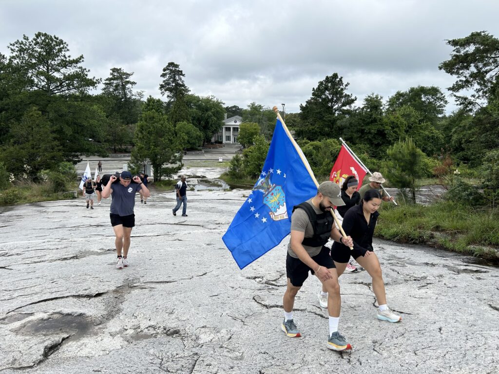 Employees march up mountain in Atlanta with flags during Memorial Day Ruck March.