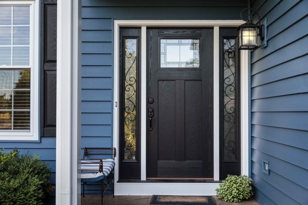 front porch of home with black door and blue siding.