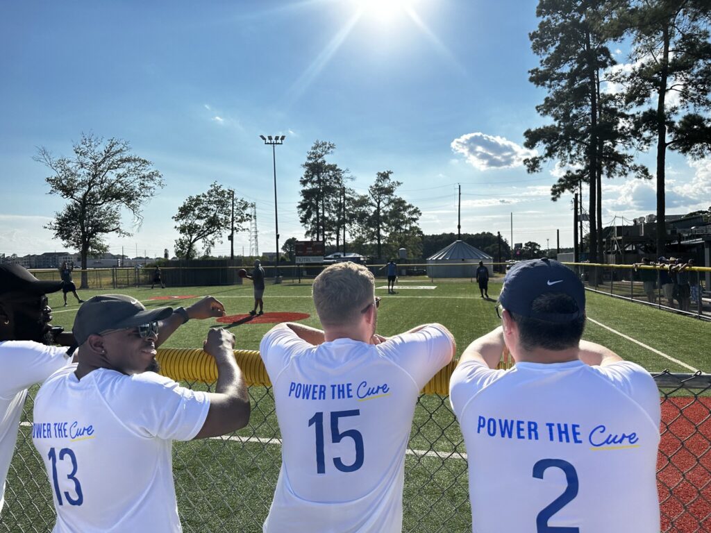 Power employees pose for a photo showing the back of their shirts that say "Power the Cure."