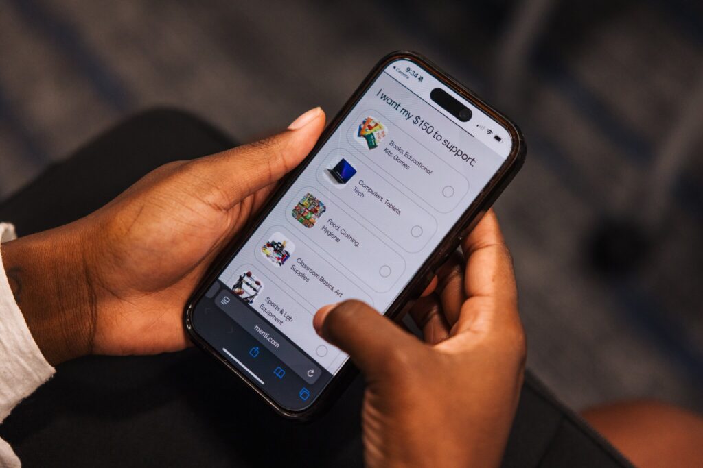 Employee uses their smart phone to choose where their $150 donation goes for a public school classroom in need.