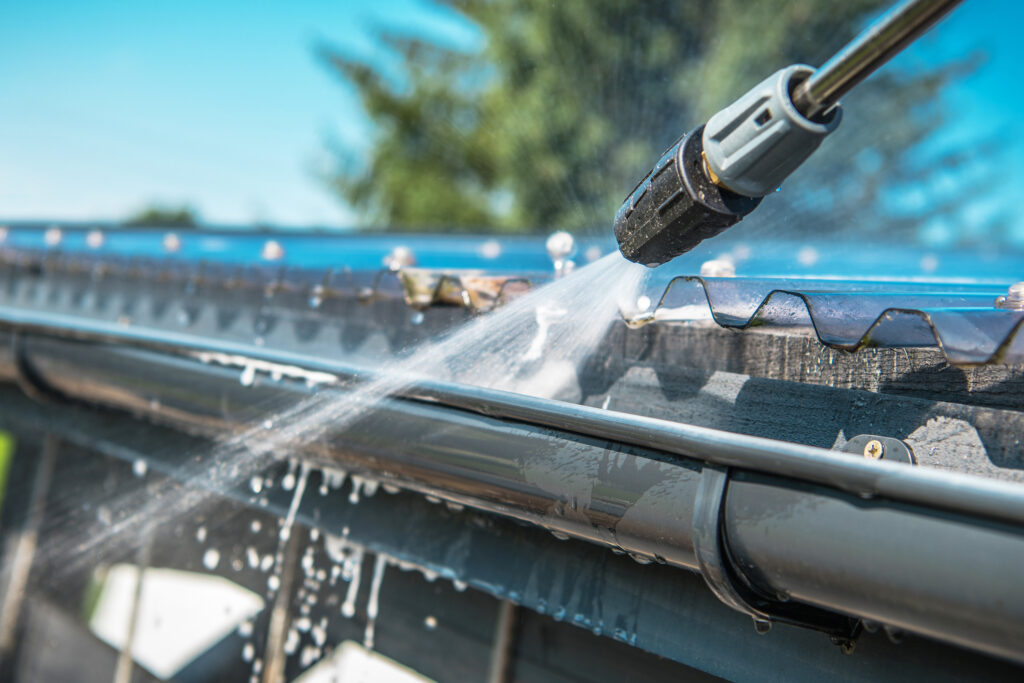 Close up of a pressure washer lightly cleaning gutters.