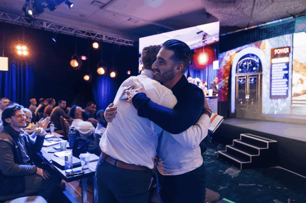 Ty and a colleague share a hug at a POWER event. 